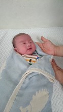 布にくるまれ抱かれている新生児