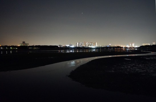 夜の川辺と街の明かりが広がる風景