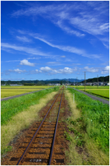 青空の下、田園地帯を通る線路の風景