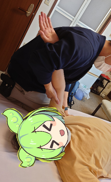 ベッドの上でリハビリのストレッチを受ける写真（顔はキャラクターイラストで隠されている）