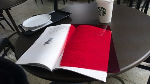 スターバックスのコーヒーと赤い本が置かれたテーブル