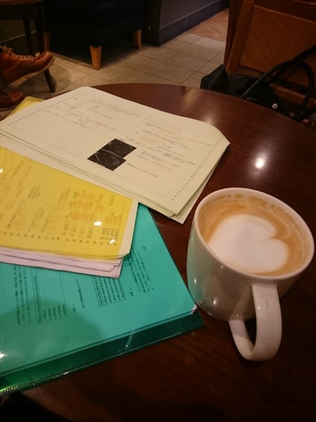 コーヒーカップと勉強道具が置かれた木目の机（別カット）