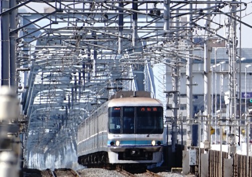複雑な架線の下を走行してくる電車
