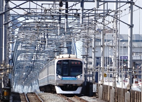 架線が複雑に張り巡らされた線路を走る電車