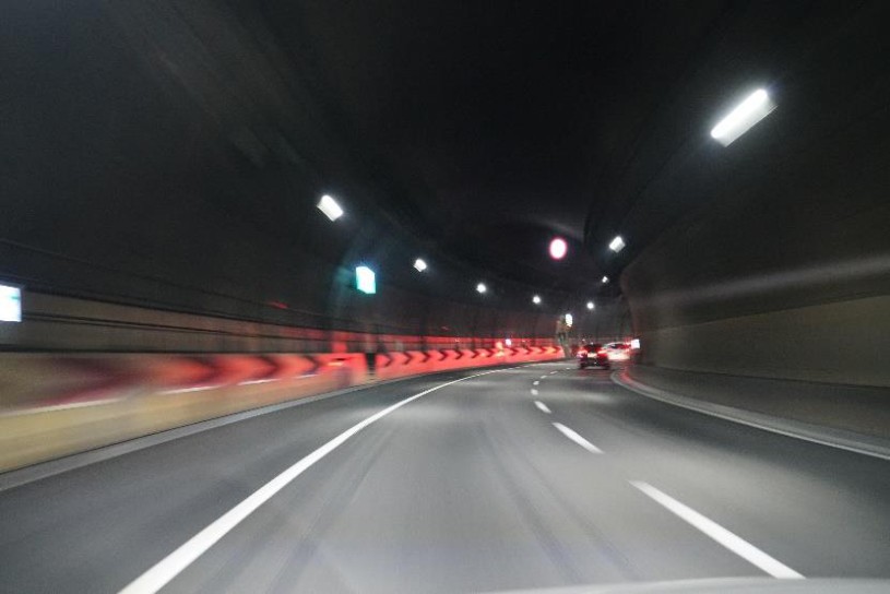 赤色灯が連なる高速道路トンネル内を走行する写真