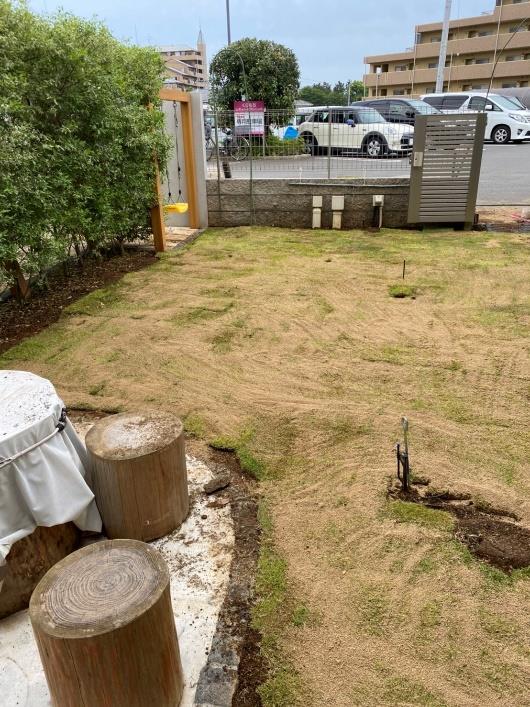 丸太の柱が置かれた、目土をかけた後の庭の写真
