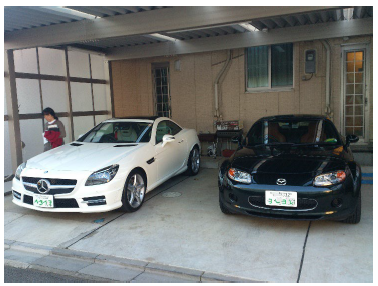 カーポートに停められた白と黒の車と人物