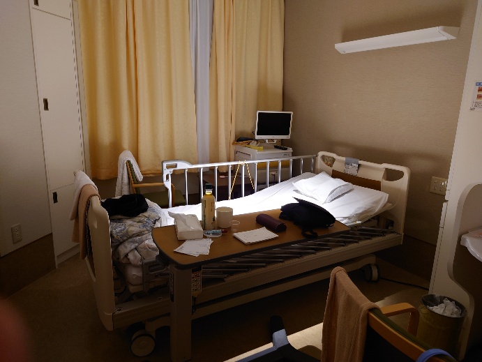 点滴スタンドと机がある病室内の写真（別カット）