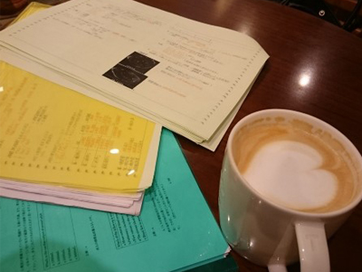 コーヒーカップと勉強道具が置かれた木目の机
